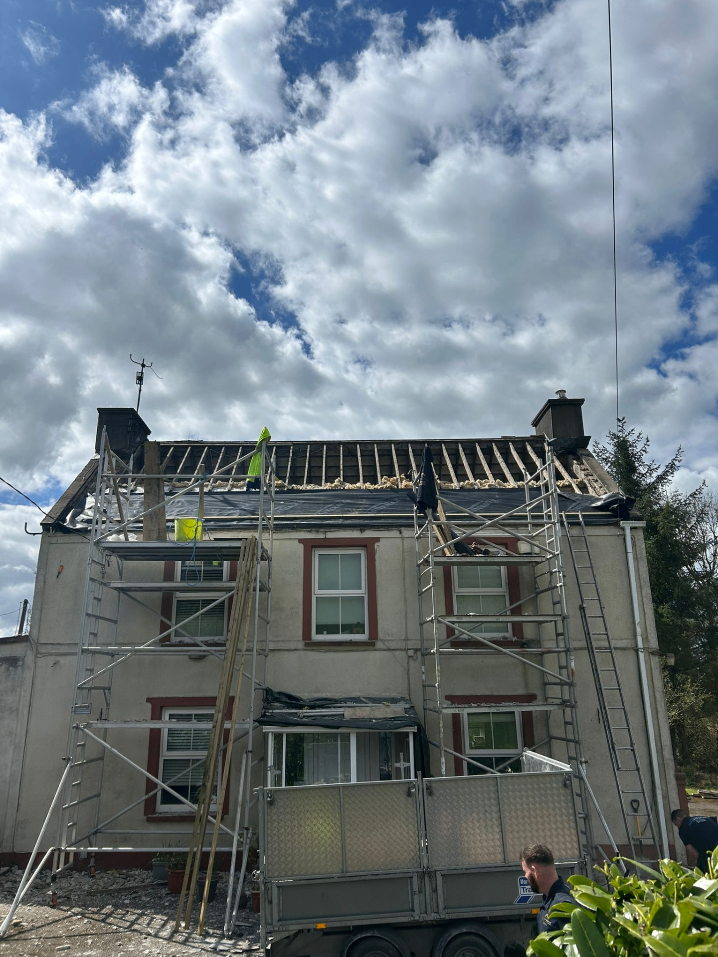 Scaffolded home with roof stripped back during renovation work